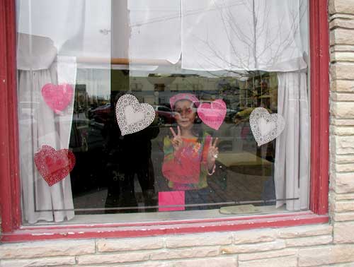 Girl in window gives peace sign.