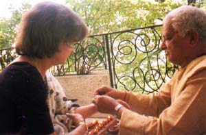 Priest tying a bracelet onto wrist (the sacred fire).