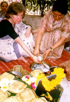 Ragini pours milk over Wilda's hand at puja.